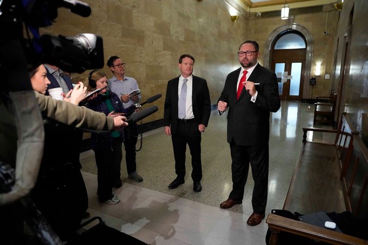 Mike Davis, center left, and Donald Trump's campaign adviser Jason Miller talk outside a courtroom before beginning an October 2023 hearing for a lawsuit that sought to keep former President Donald Trump off a state ballot.