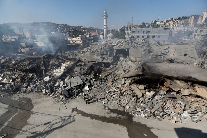 Hezbollah rescue workers search for victims amid the rubble of destroyed buildings at commercial street that was hit Saturday night by Israeli airstrikes, in Nabatiyeh town, south Lebanon, Sunday, Oct. 13, 2024. (AP Photo/Mohammed Zaatari)