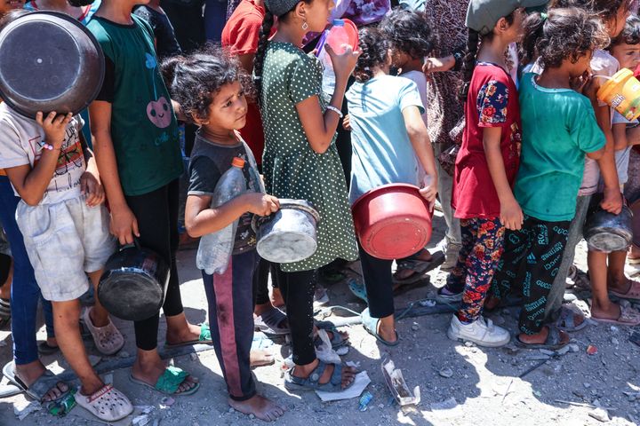 Palestinian children stand in line with their pots at a food distribution point in the northern Gaza's Jabalia refugee camp on August 21, 2024.