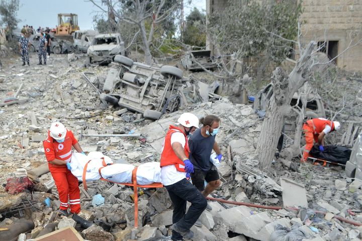 Paramedics with the Lebanese Red Cross transport a body unearthed from the rubble at the site of an Israeli airstrike targeting the northern Christian-majority village of Aito, on October 14, 2024.