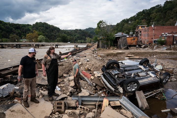 People search for missing items from a mechanic's shop in Marshall, North Carolina, in the aftermath of Helene.